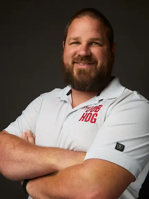 Chris Powell, smiling with his arms crossed, in a white Job Hog polo