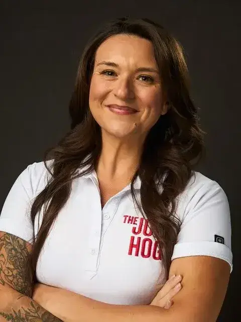 Julia Douglas, smiling with her arms crossed, in a white Job Hog polo