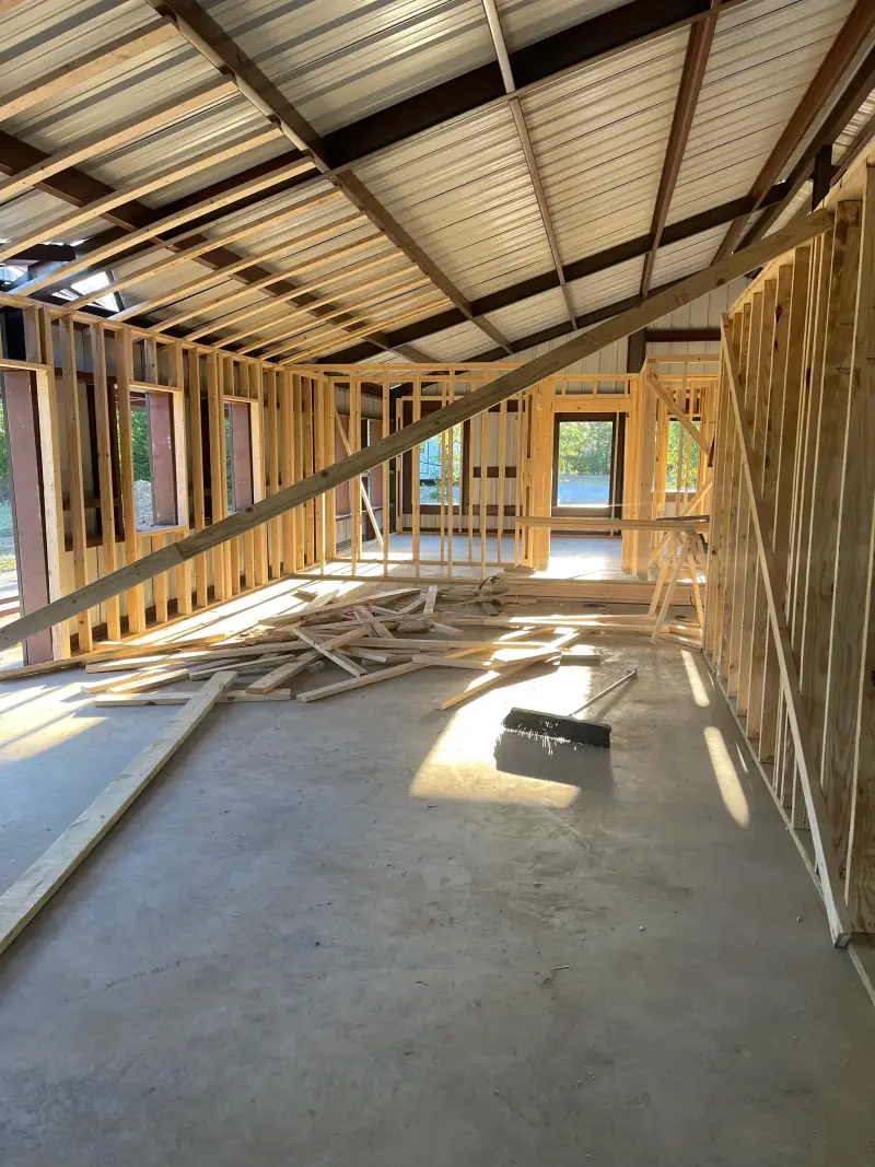 Exposed wood wall framing and window openings beneath a metal roof during construction.