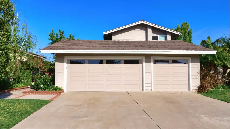 An attached three-car garage with a double-width door, a single-width door, and a concrete driveway.