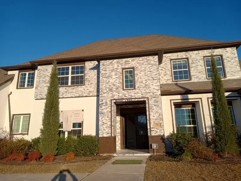 Two-story brick and stone home with dark-framed, divided-light windows across both floors.