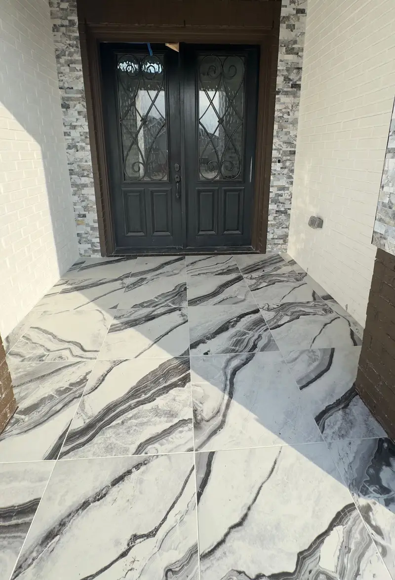 Front entry with black-and-white 2 by 4 ft marble floor tiles, stacked stone trim and black iron double doors