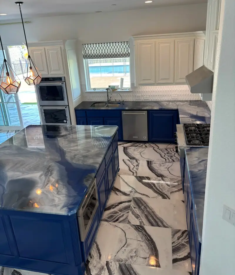 Kitchen with navy blue cabinets, glossy marble-look epoxy countertops, black-and-white 2 by 4 ft marble floor tiles and geometric pendant lights